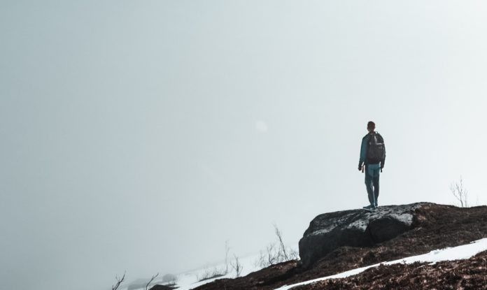 Man standing on cliff in fog